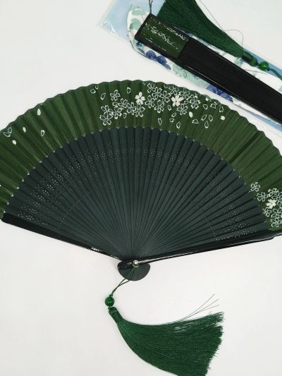 White floral tassels, dark green folding fan